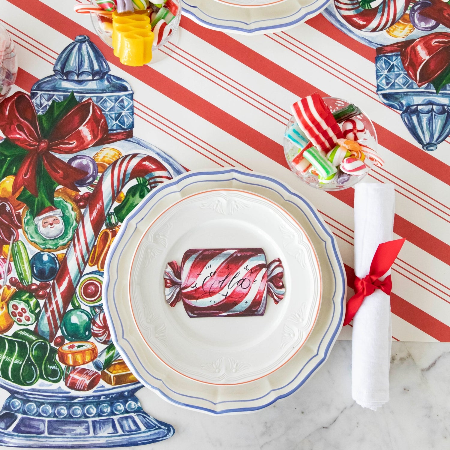 A festive place setting featuring a Christmas Candy Place Card laying flat on the plate, from above.