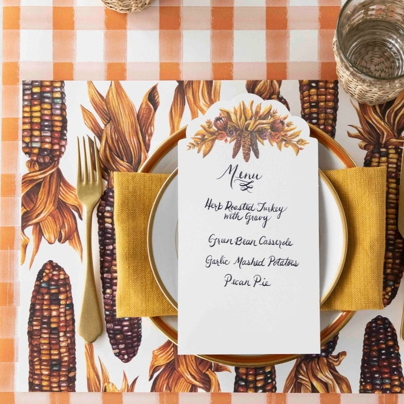 A Gathering Table Card with a menu written on it resting on the plate of an elegant Fall place setting.