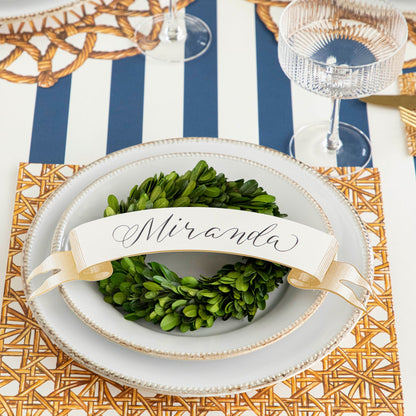 Classic Gold Banner Table Accent with &quot;Miranda&quot; written on it, on stack of plates on a rattan themed place setting.