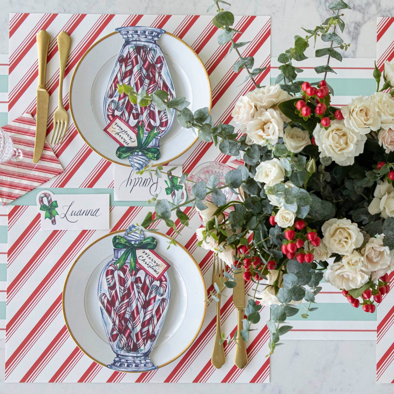 An elegant table setting with a floral arrangement, Peppermint Stripe Placemat on the Seafoam &amp; Gold Awning Stripe Runner, with the Candy Cane Jar Table Accent on a gold rimmed plate.