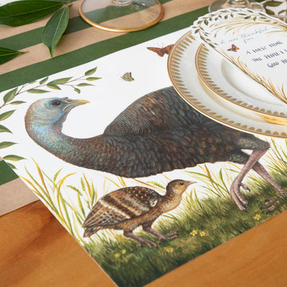 Close-up of the Heritage Hen Placemat under an elegant fall-themed place setting, showing the mother turkey and a chick.