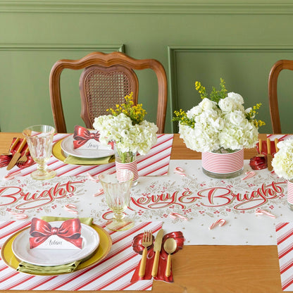 A peppermint stirpe themed table setting with the Bow Place Card on the dinner plates and Bow Table Accent underneath silverware.