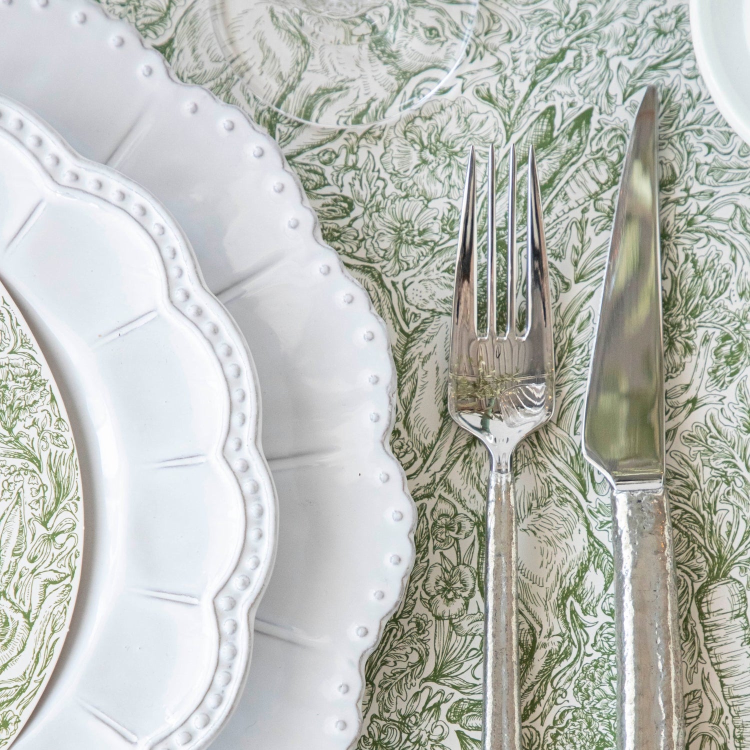 A densely-packed illustration of rabbits, flowers, carrots and foliage, in medium green over white.