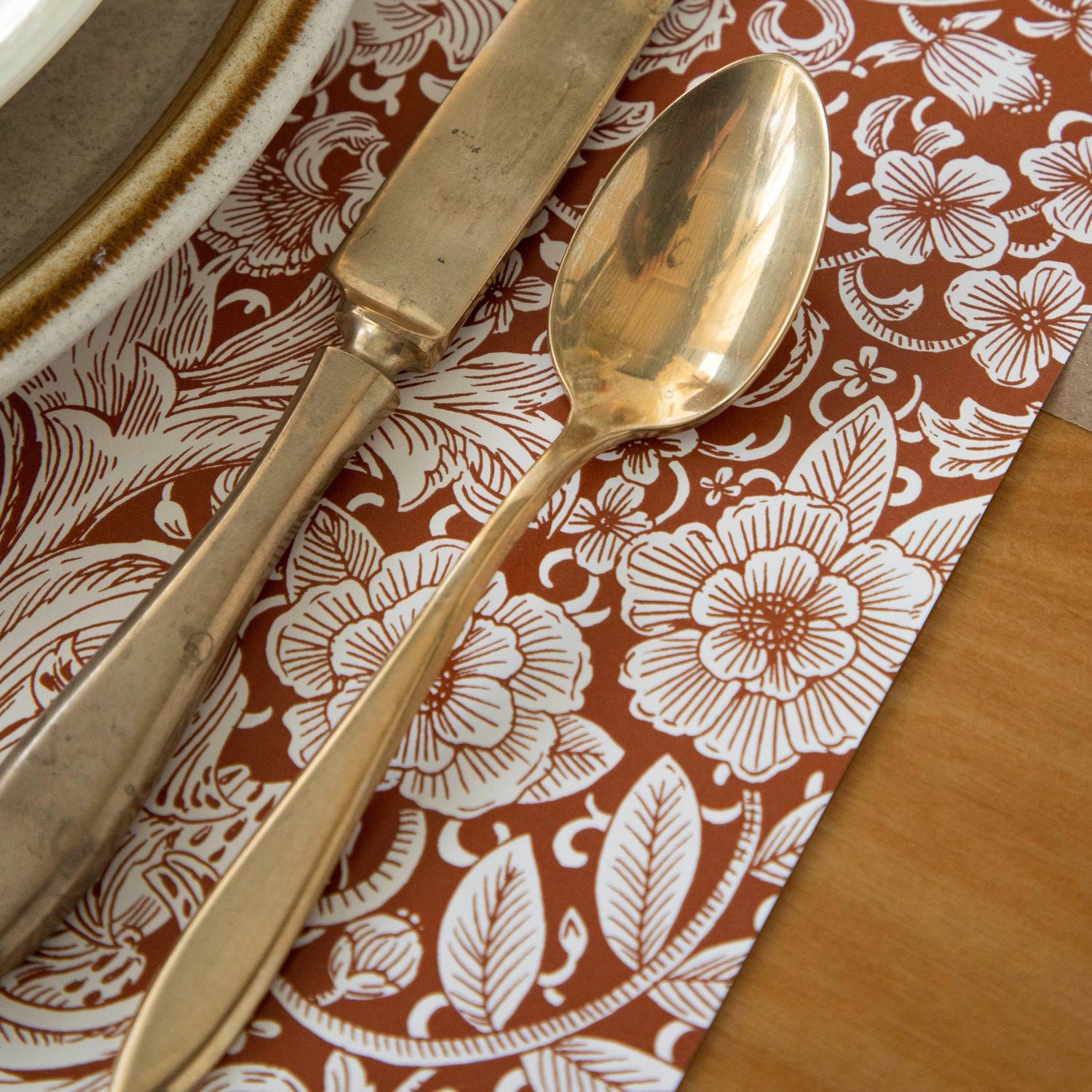 Close-up of the Harvest Bouquet Placemat under a fall-themed place setting with brass flatware.