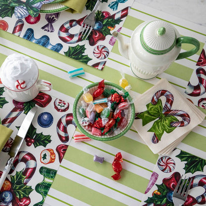 A festive Christmas-themed tablescape featuring a stack of Candy Cane Cocktail Napkins fanned out on the table.