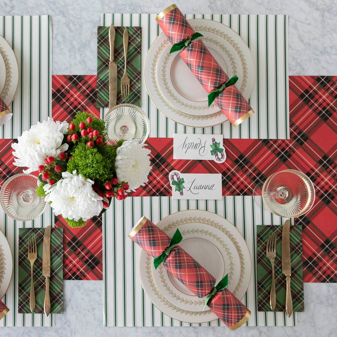 The Green Ribbon Stripe Placemat under an elegant table setting featuring red and green plaid.