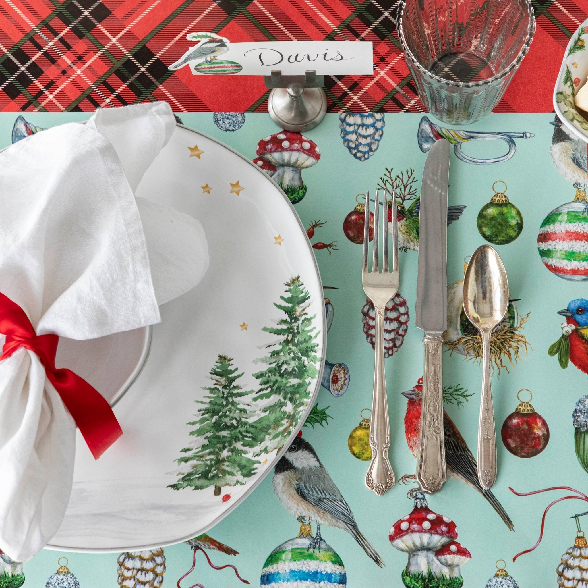 A Christmas themed table setting featuring the Baubles and Birds Placemat on the Red Plaid Runner.