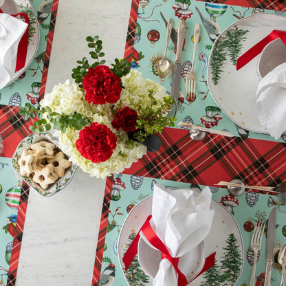 An elegant table setting featuring flowers and star-shaped cookies in the center, and the Baubles and Birds Placemat on the Red Plaid Runner.