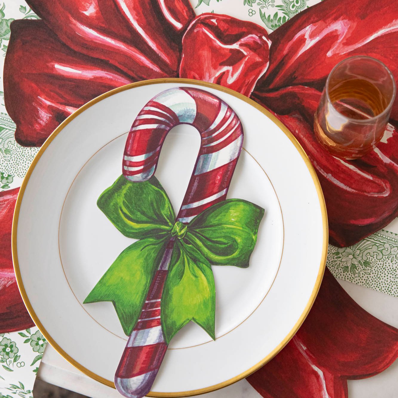 The Candy Cane Table Accent resting on a plate that sits on top of the Die-cut Christmas Bow Placemat.