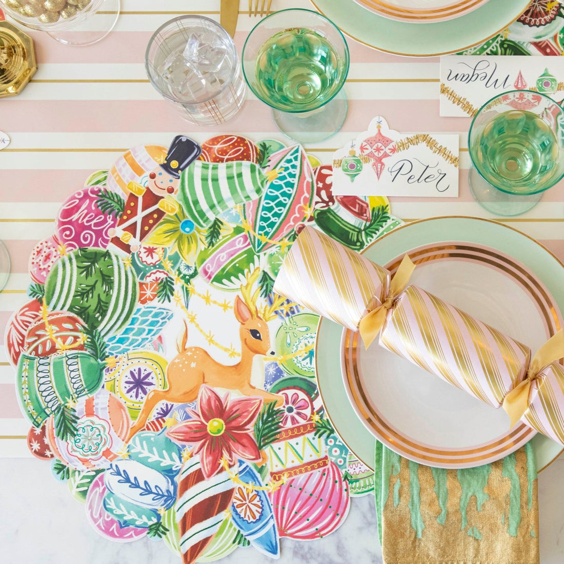 A nostalgic themed place setting featuring the Die-cut Yuletide Treasure Wreath Placemat under dinner plates with a marbled napkin in between and a pink &amp; gold stripe festive cracker resting on top.