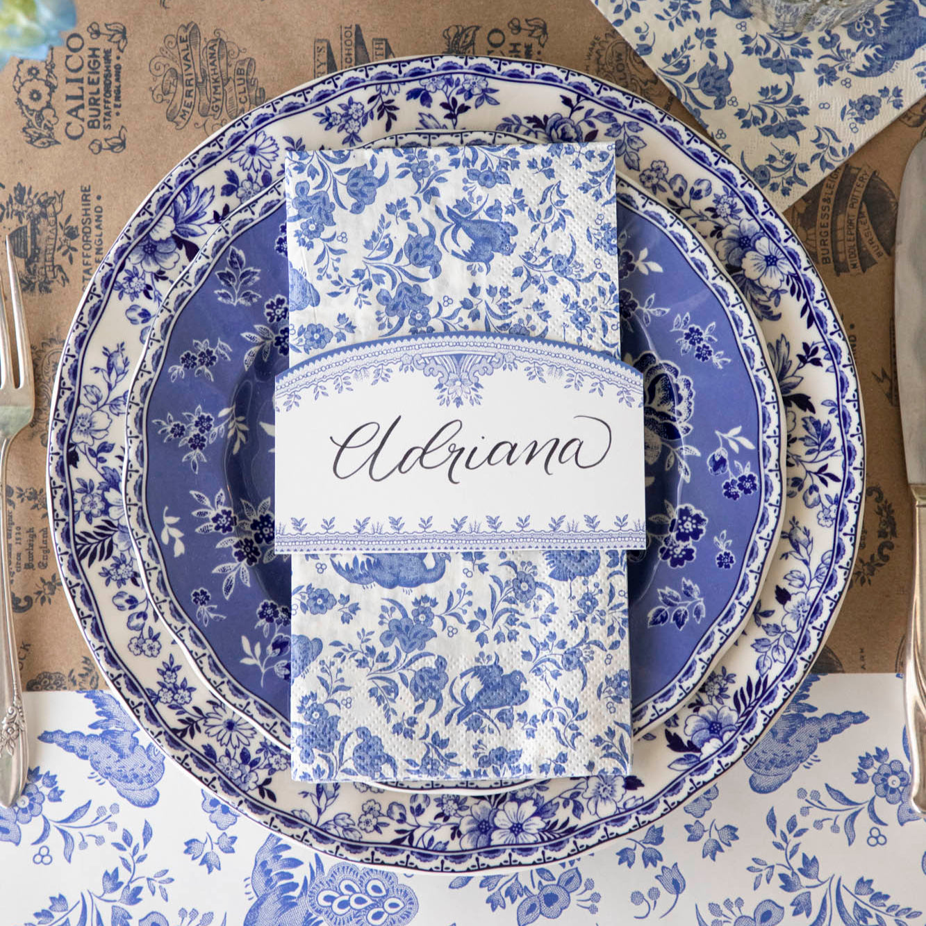 Burleigh Blue Place Card with &quot;Adriana&quot; written on it, resting on a place setting for one.