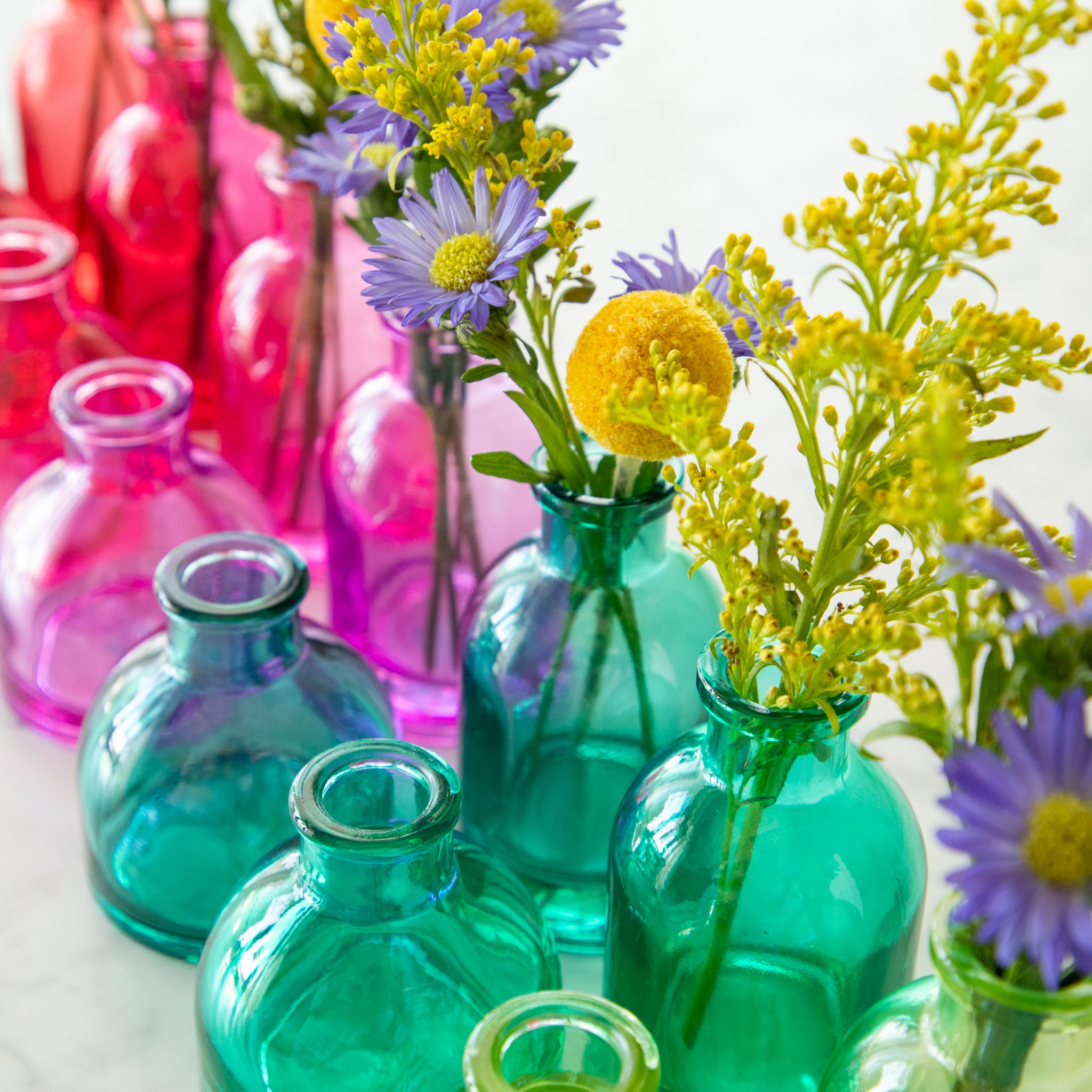 Tall and round Jewel Tone Glass Bud Vases ranging from colors red to blue.