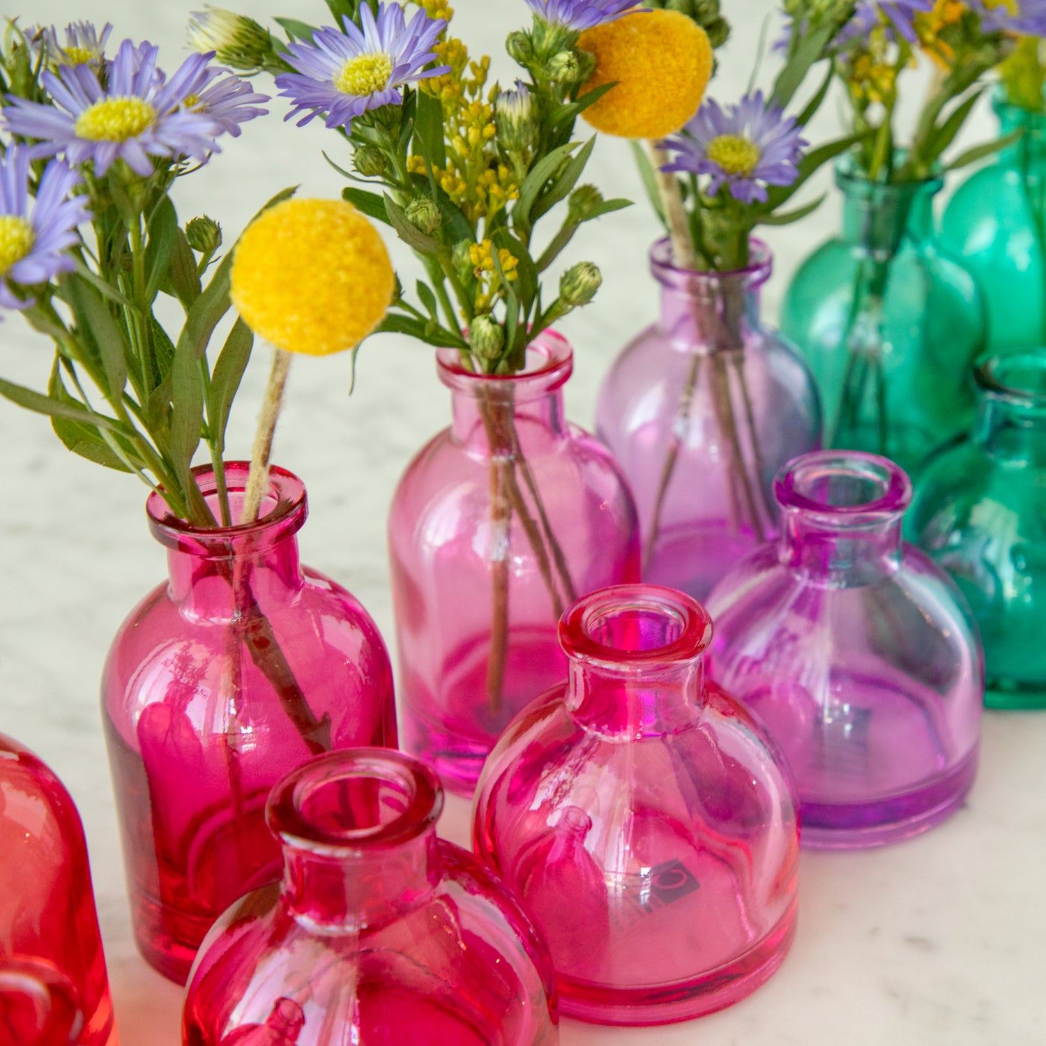 Tall and round Jewel Tone Glass Bud Vases ranging from colors red to blue.