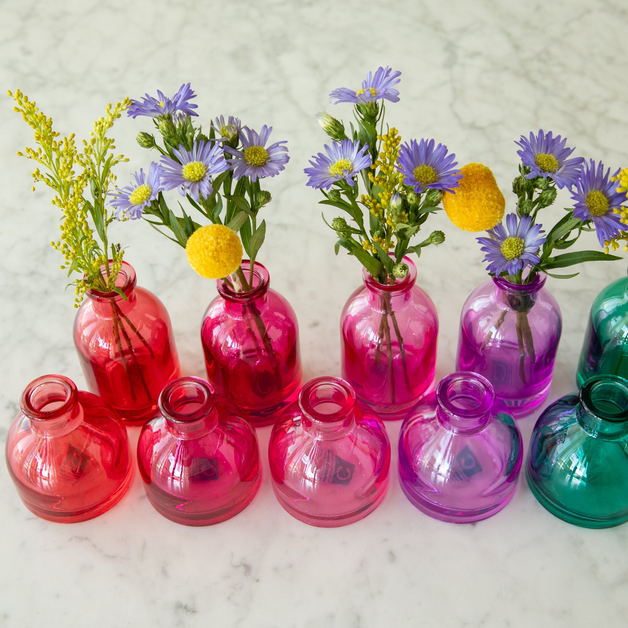 Tall and round Jewel Tone Glass Bud Vases ranging from colors red to purple.