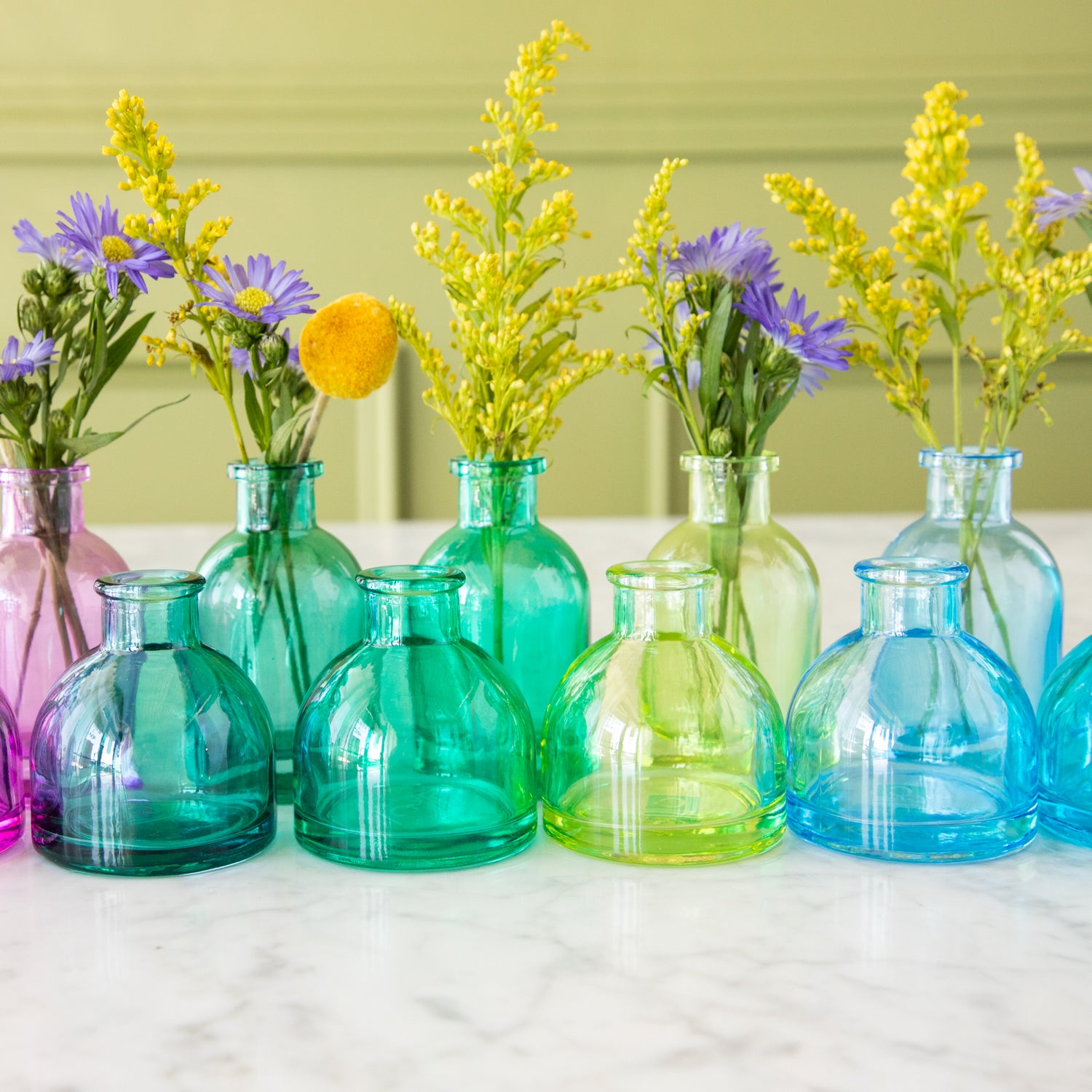 Tall and round Jewel Tone Glass Bud Vases ranging from green to blue.