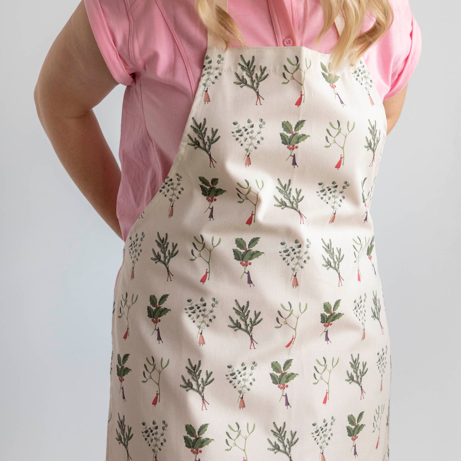 A woman tying the Laura Stoddart Christmas Apron behind her back.