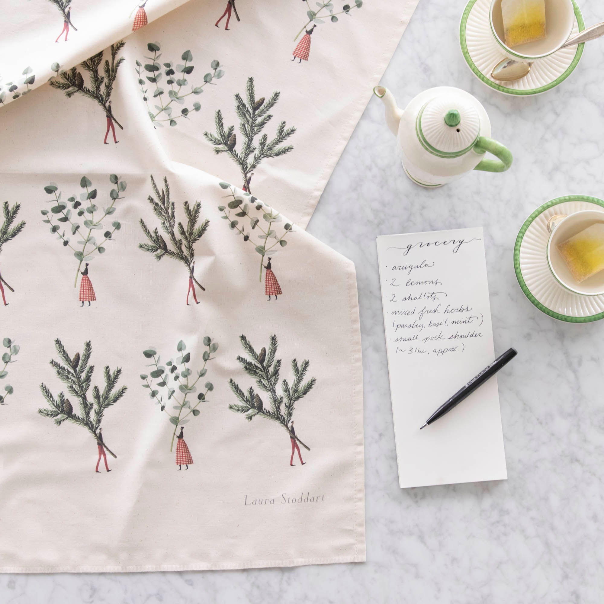 Laura Stoddart Spruce &amp; Eucalyptus Multi Tea Towel next to a grocery list and tea cups.