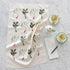 The Laura Stoddart Holly & Mistletoe Multi Tea Towel next to a grocery list, tea cups and a creamer pot.