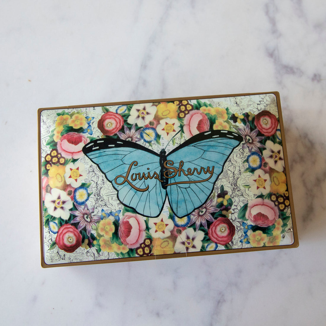 12-Piece John Derian Butterfly Louis Sherry Chocolate Box on a marble table.