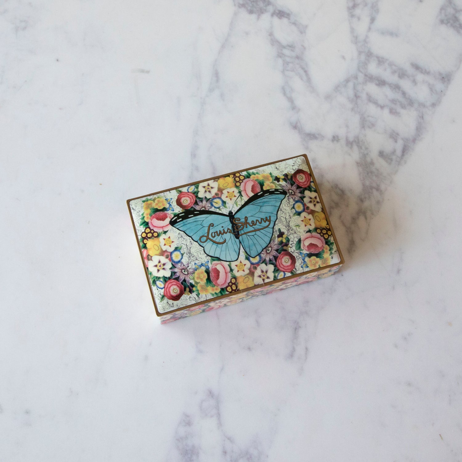 12-Piece John Derian Butterfly Louis Sherry Chocolate Box on a marble table.