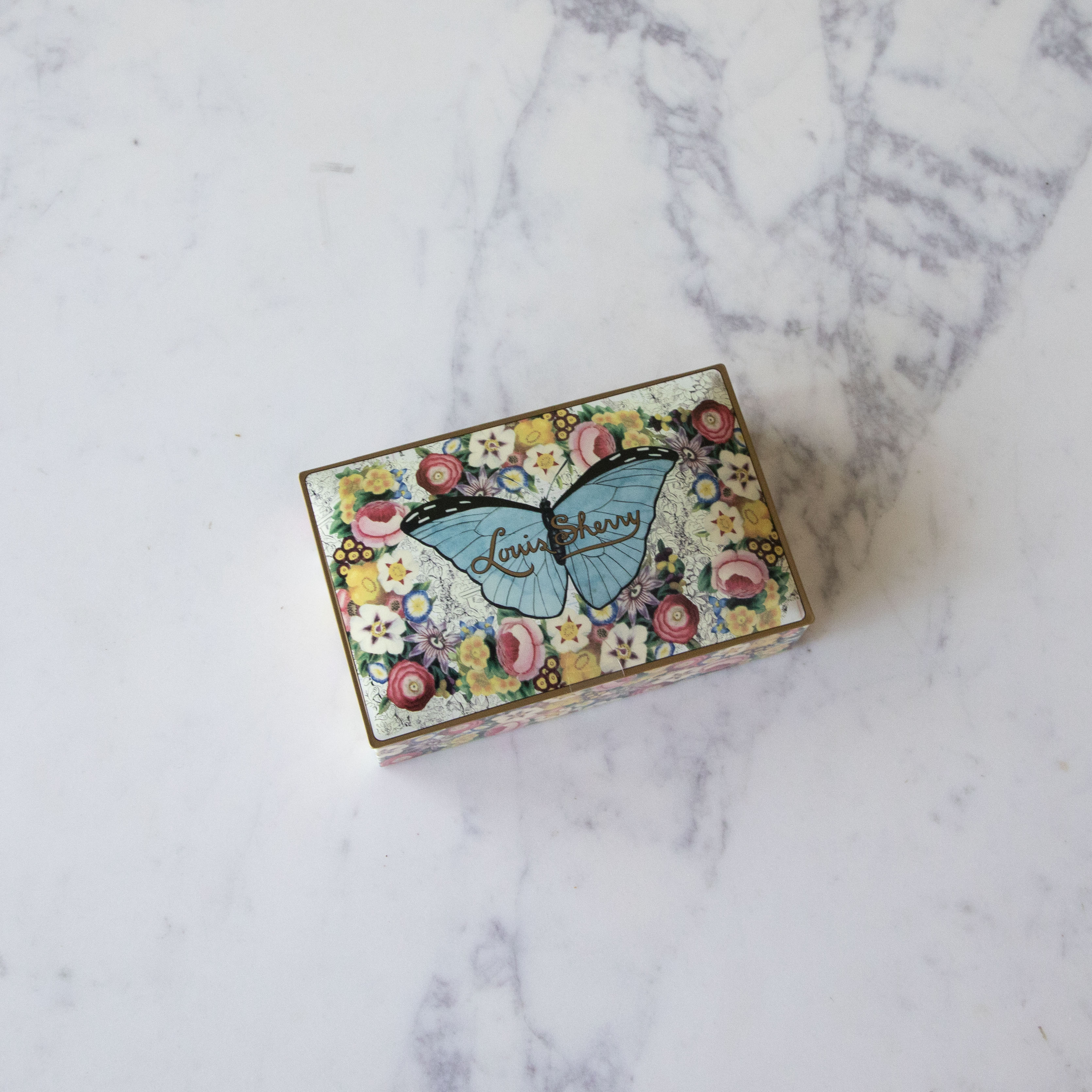 12-Piece John Derian Butterfly Louis Sherry Chocolate Box on a marble table.