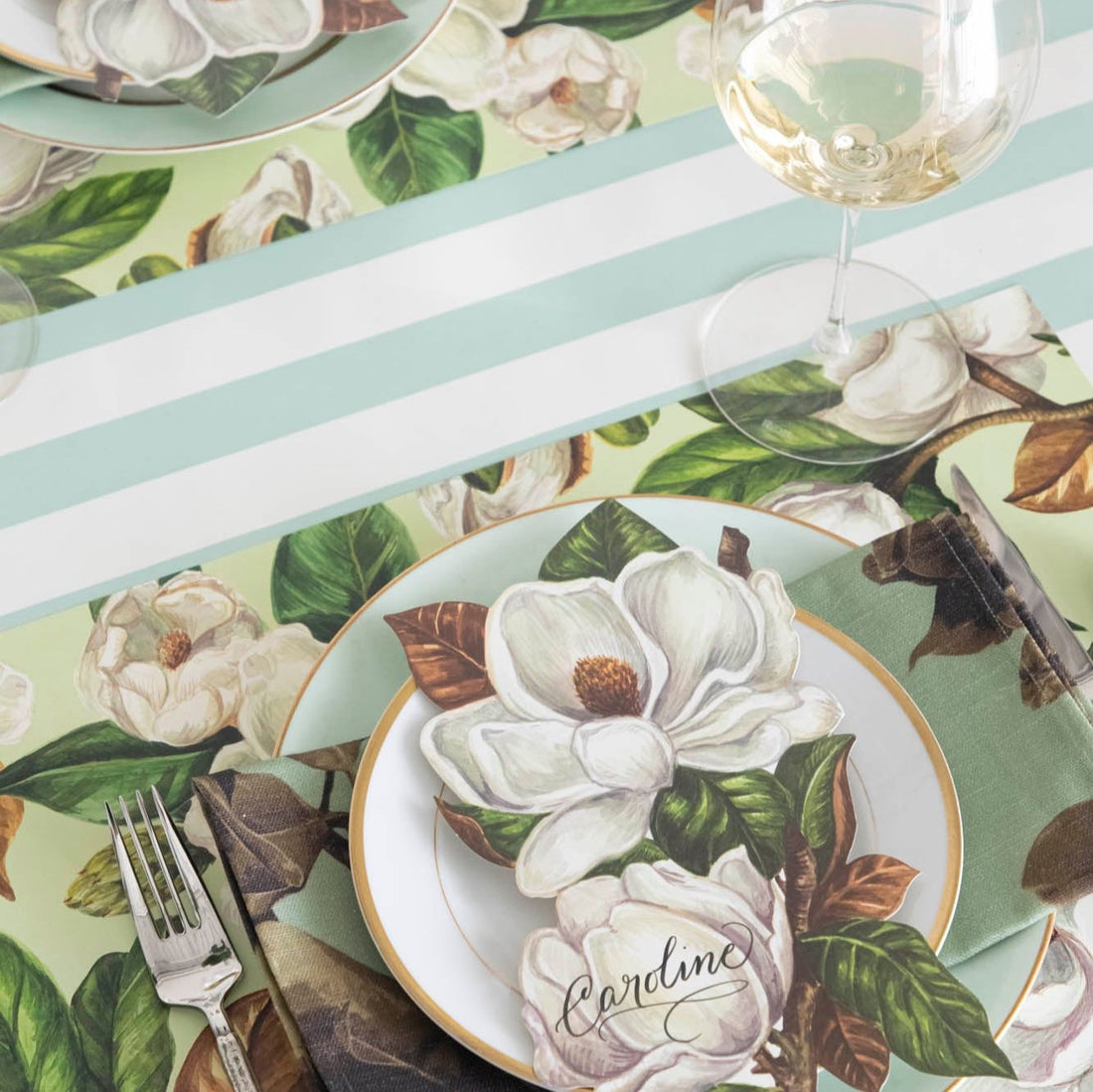 The Seafoam Classic Stripe Runner with Magnolia Blooms Placemat and table accent on top.