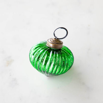 Mini green ribbed ornament on a marble table.