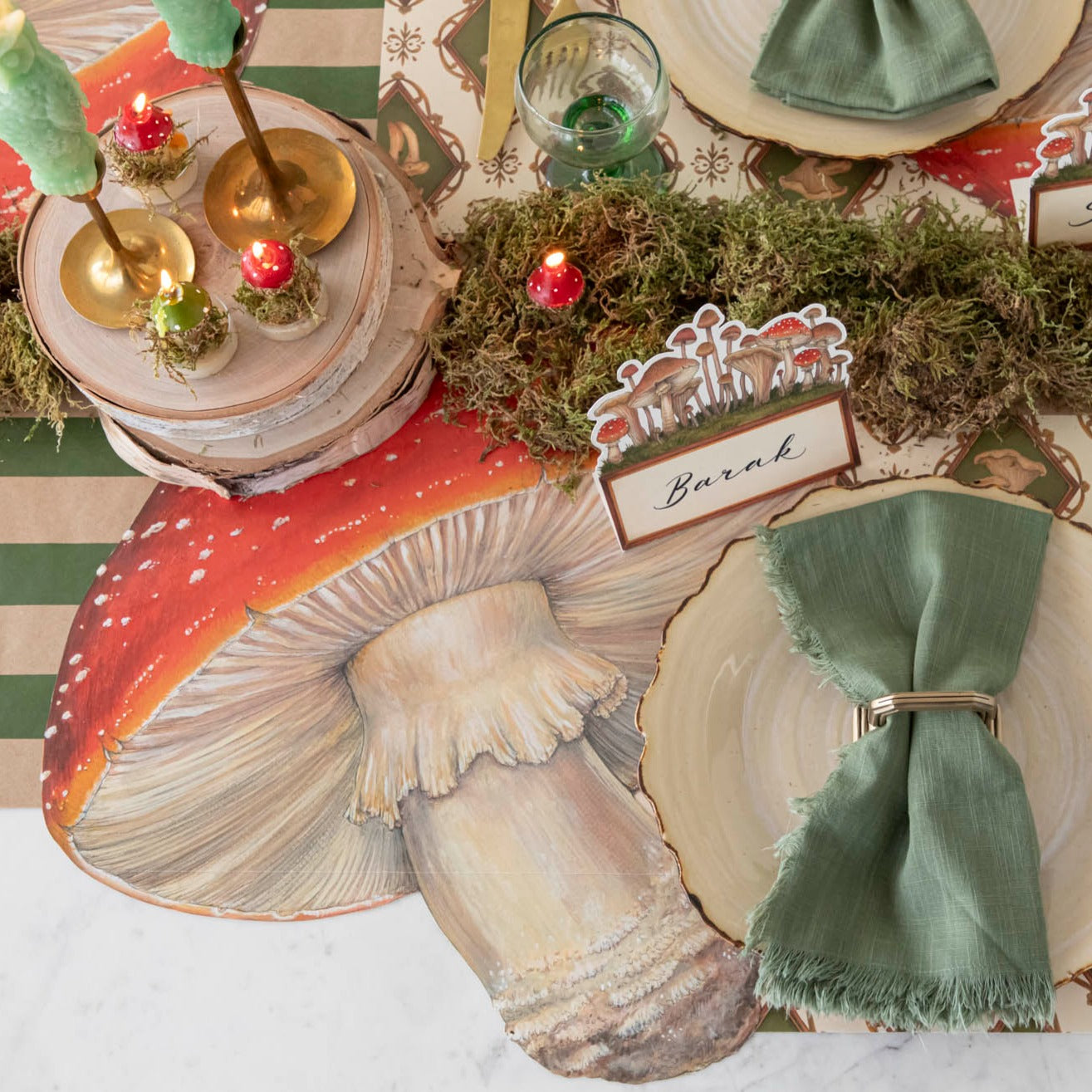 A die-cut mushroom placemat is placed on a kraft green runner, surrounded by moss, with a plate topped with a green napkin.
