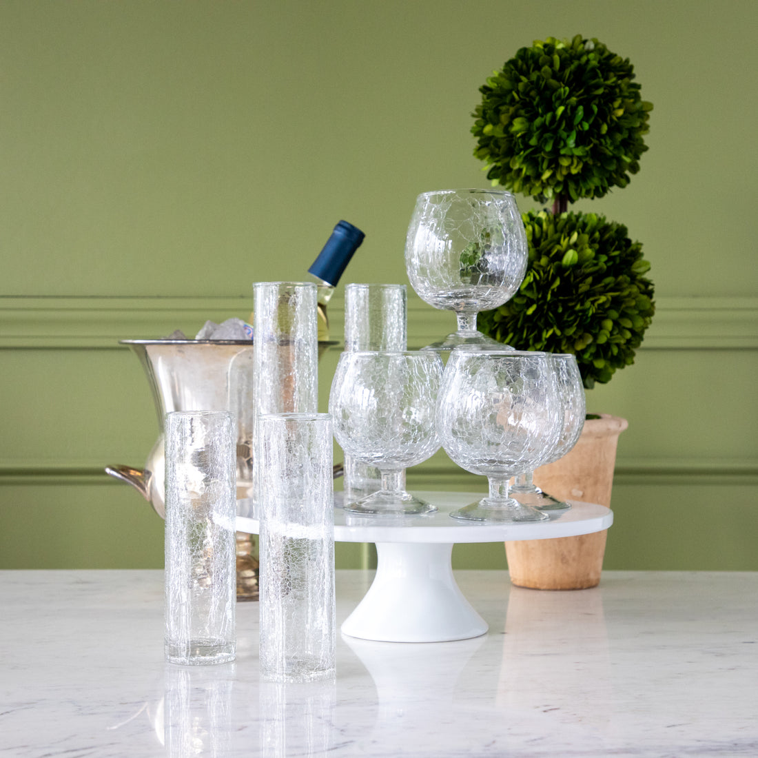 Norwell Goblet and Champagne Flutes in front of a champagne bucket and boxwood.