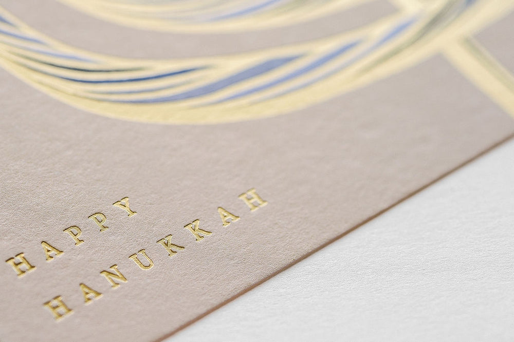 Close up of the letterpress words Happy Hanukkah in gold