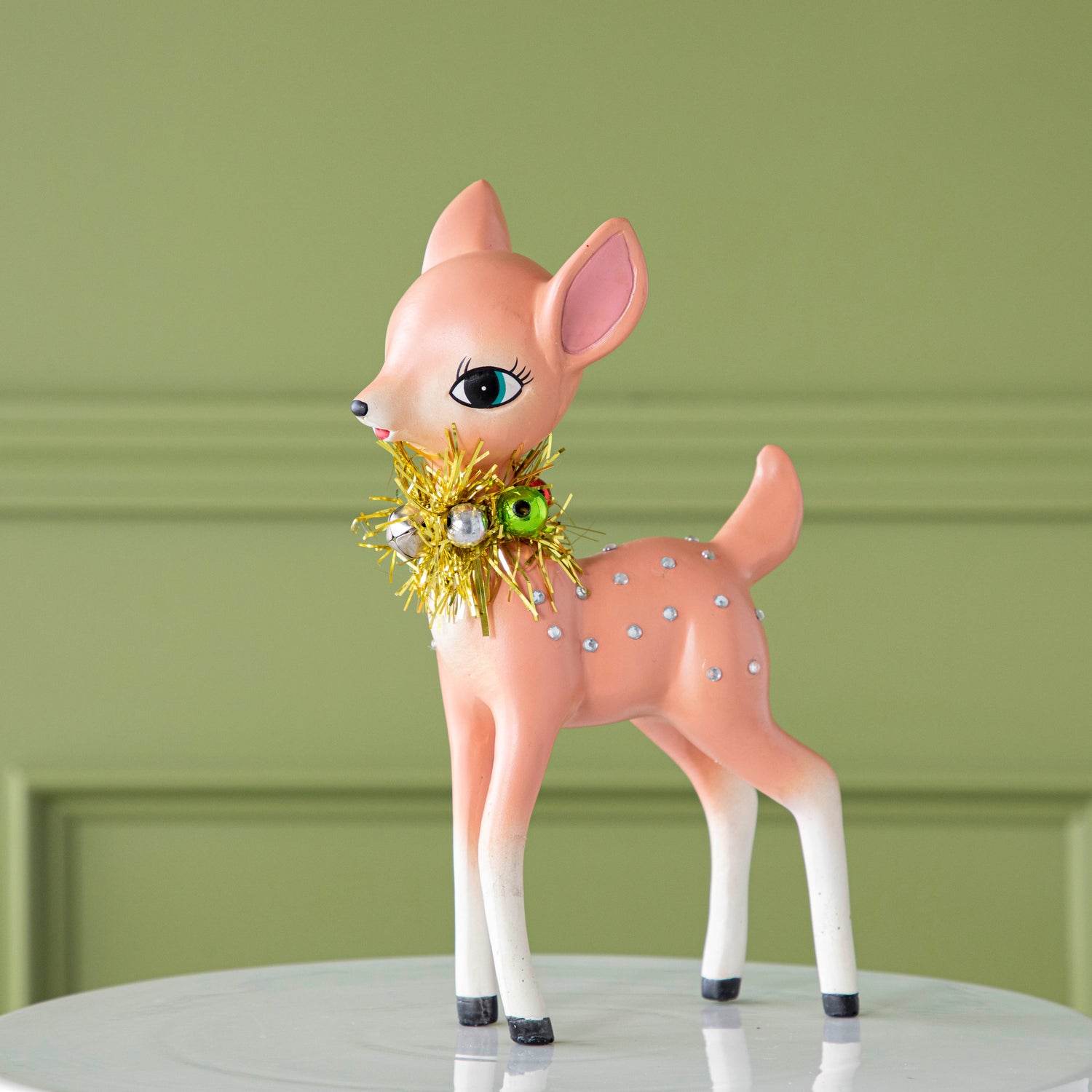 The pink Retro Reindeer with a tinsel wreath with ornaments around its neck and jeweled body.