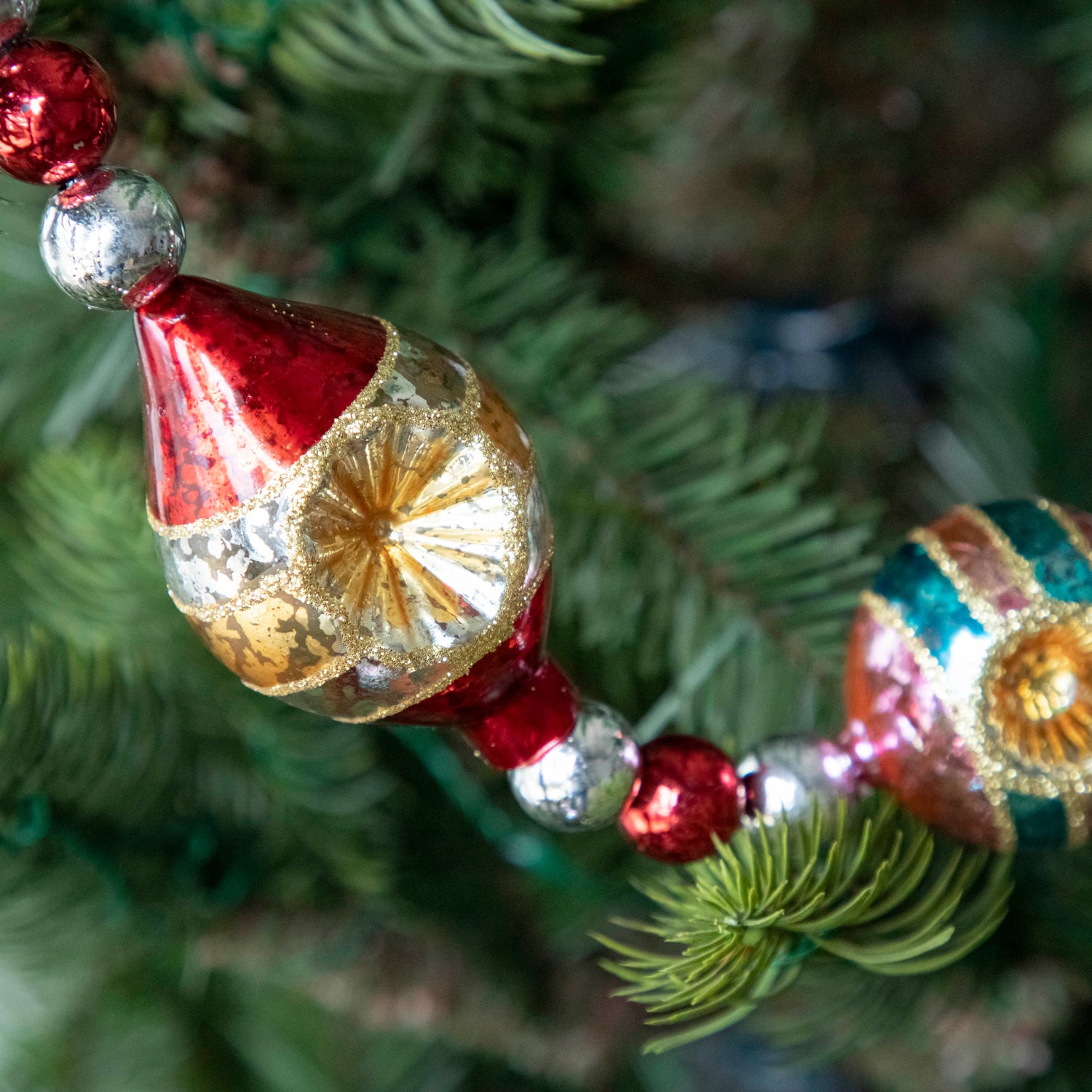 A close up of the Retro Tinsel and Glass Finial Garland showing its 50s style bulb.