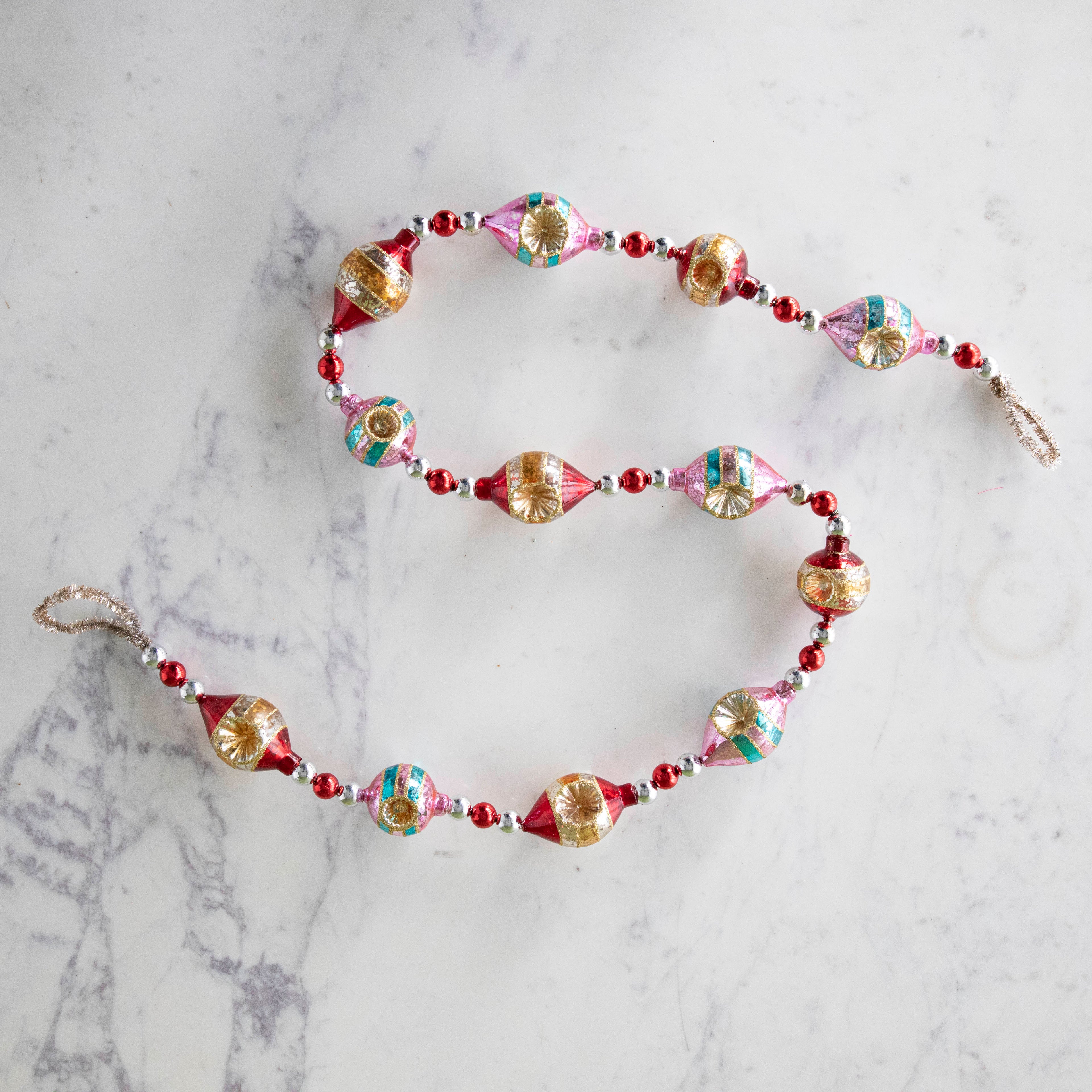 The  Retro Tinsel and Glass Finial Garland on a marble table.