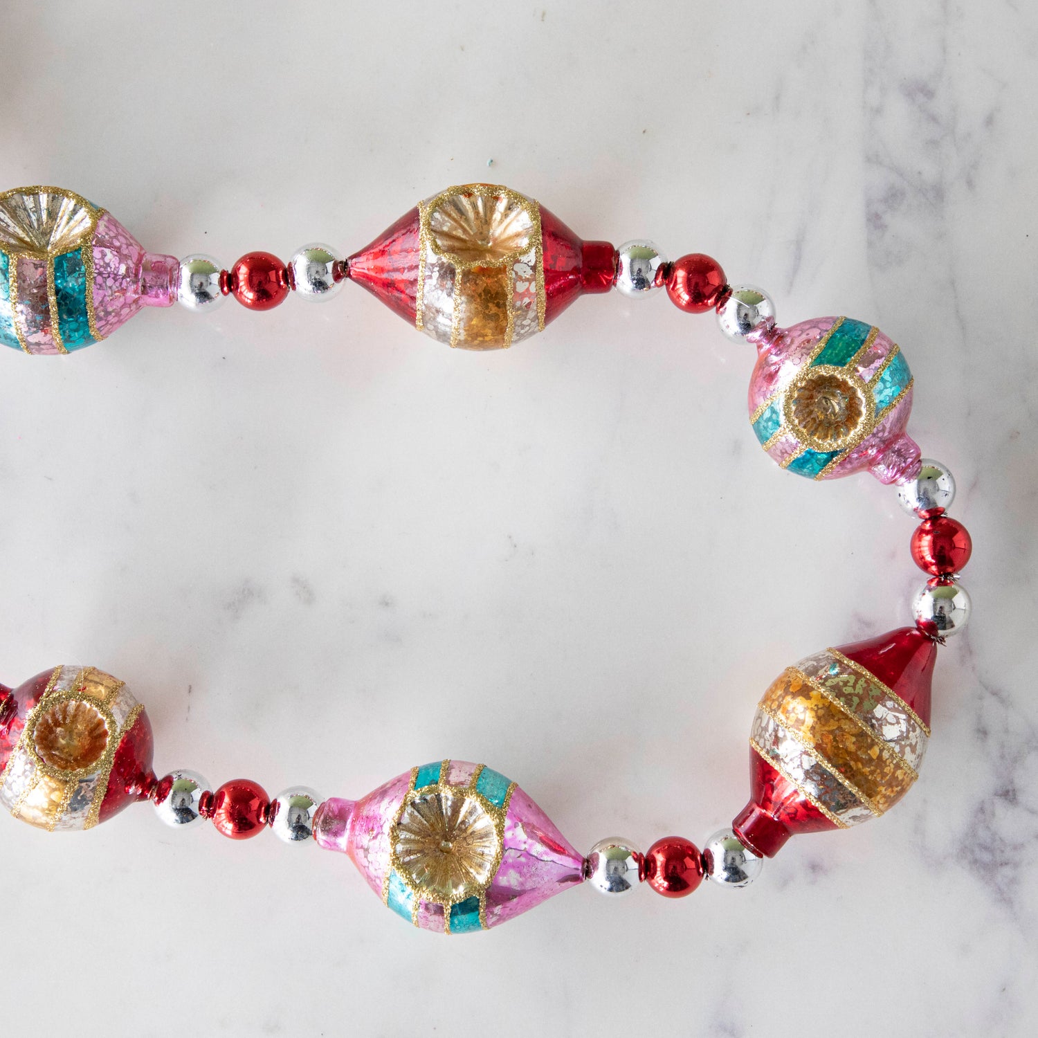 The Retro Tinsel and Glass Finial Garland on a marble table.