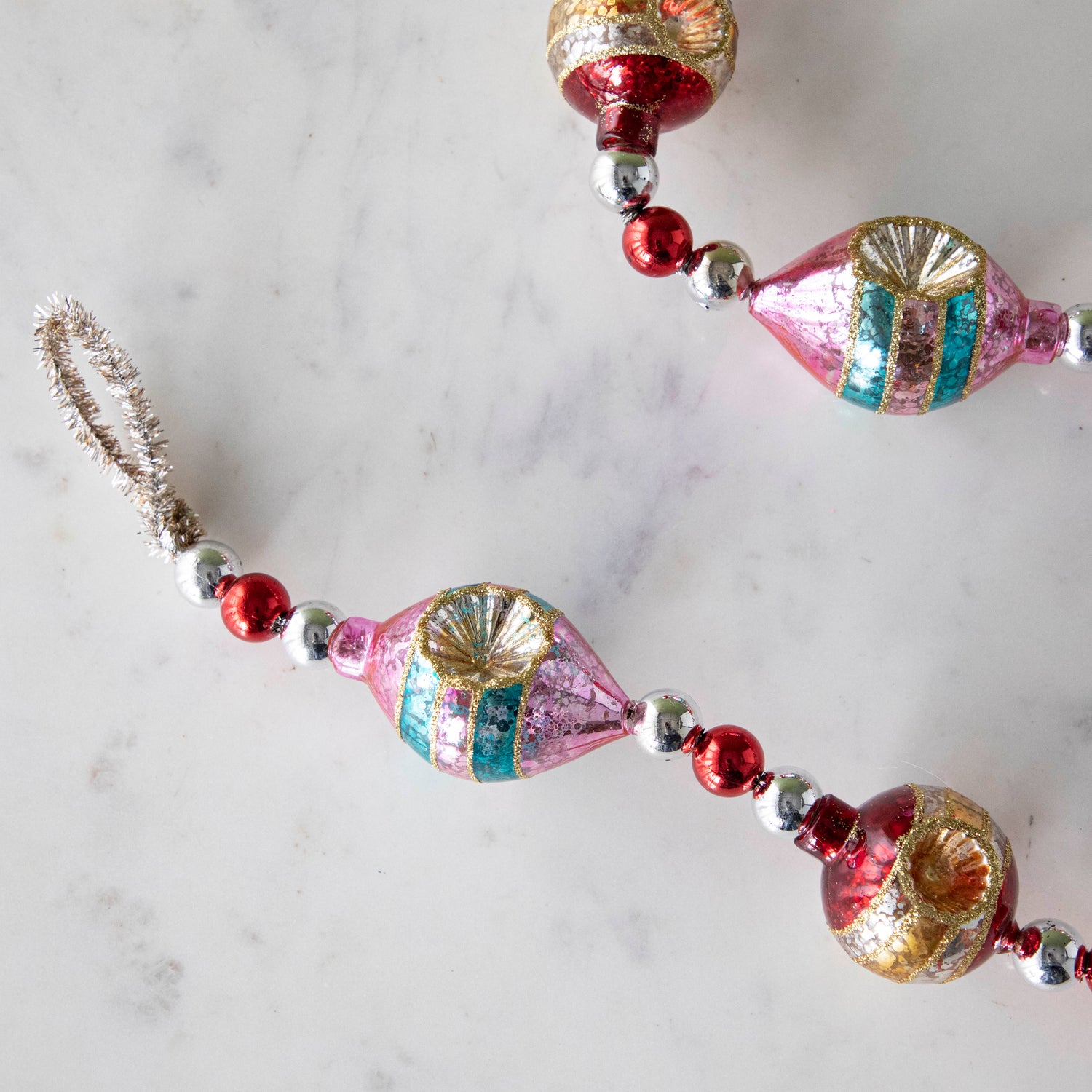 The  Retro Tinsel and Glass Finial Garland on a marble table.