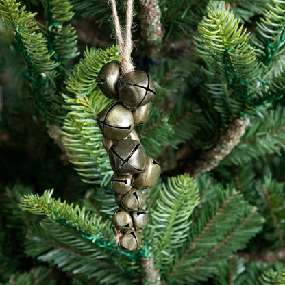 A Jingle Bells Ornament hanging on a tree by a tweed hook.