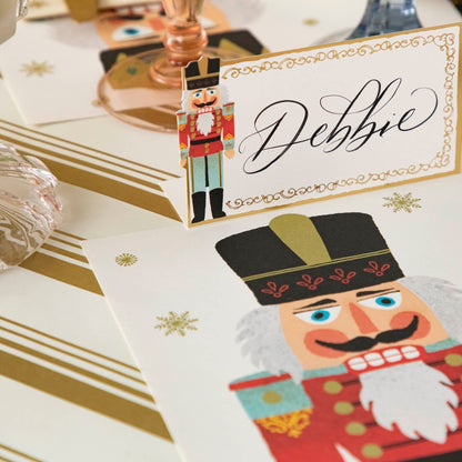 The Gold Peppermint Stripe Runner under the Nutcracker Place Card with the name &quot;Debbie&quot; written on it in cursive and the Nutcracker Placemat.