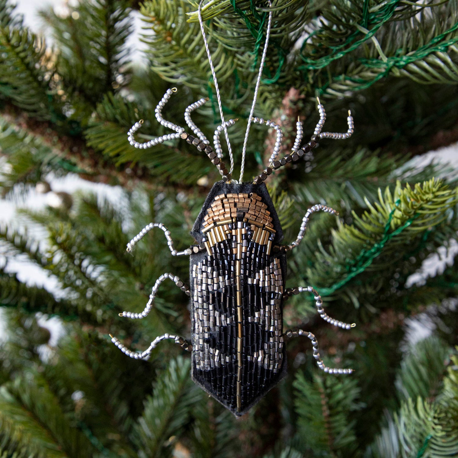 The Beaded Insect Ornament hanging on a tree.