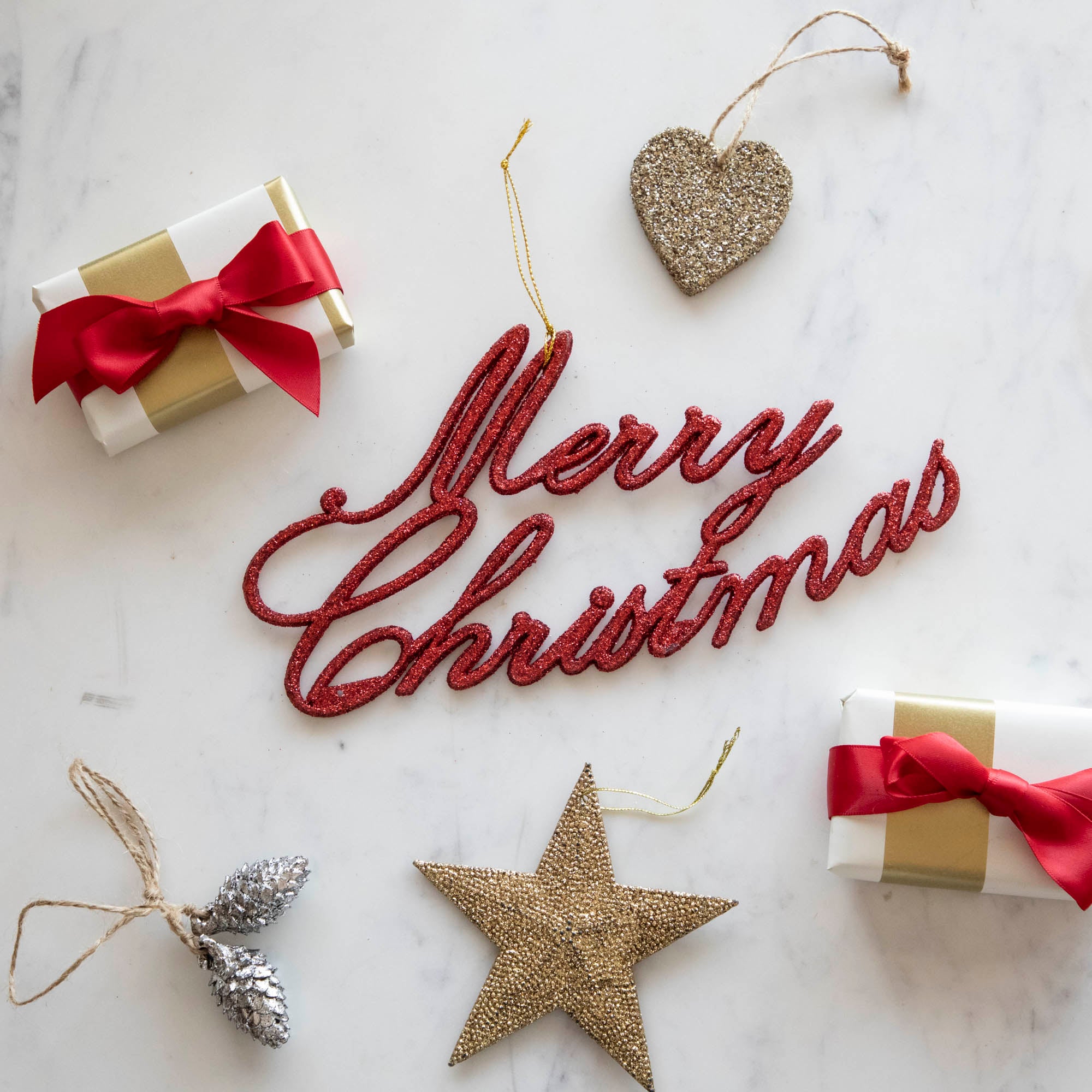 The Merry Christmas Red Ornament surrounded by small presents and festive ornaments.