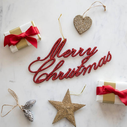 The Merry Christmas Red Ornament surrounded by small presents and festive ornaments.