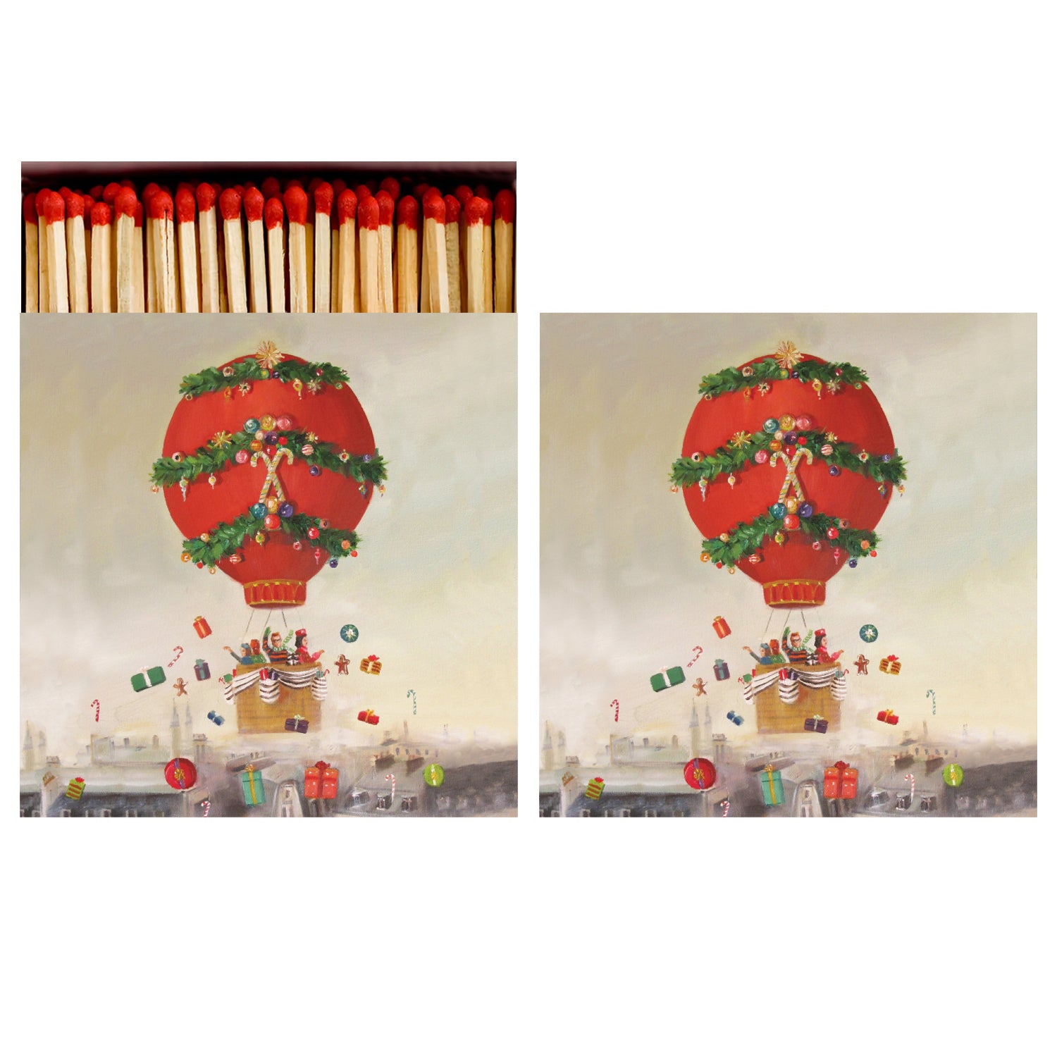 Two identical sides of a square match box, the left of which is open slightly to reveal the matches inside. The artwork on the box depicts a festive bright red hot air balloon adorned with Christmas decorations floating high above a town.