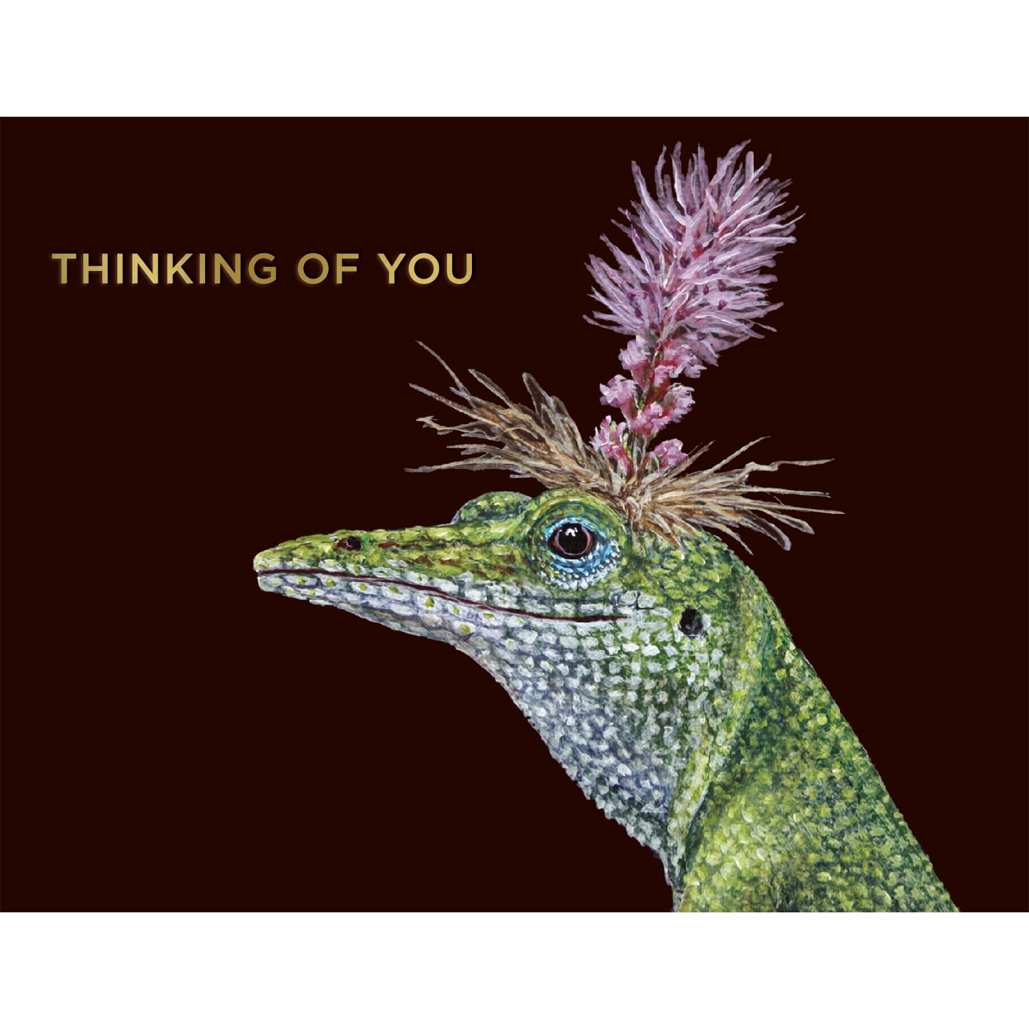 A dark brown greeting card featuring a charming illustrated portrait of a green lizard wearing a pink bloom as a hat, with the words &quot;THINKING OF YOU&quot; printed in gold foil. 