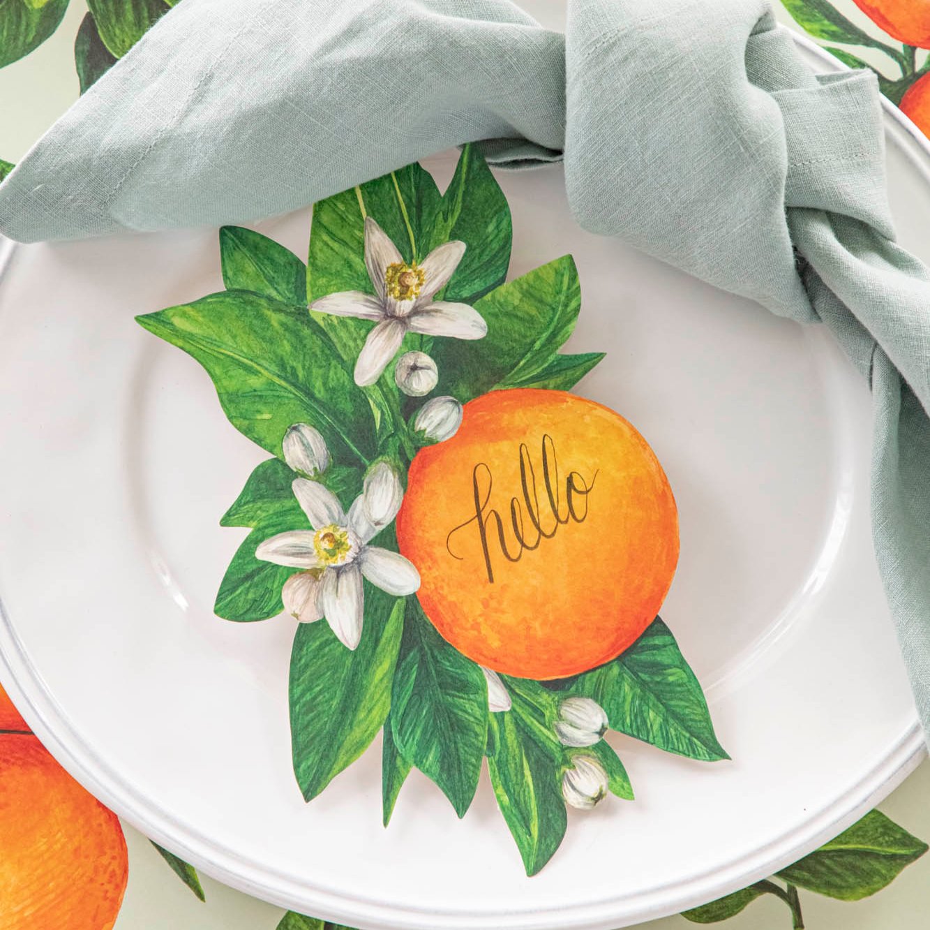 A close up of the Orange Blossom Table Accent with &quot;hello&quot; written in cursive in the center of the orange.