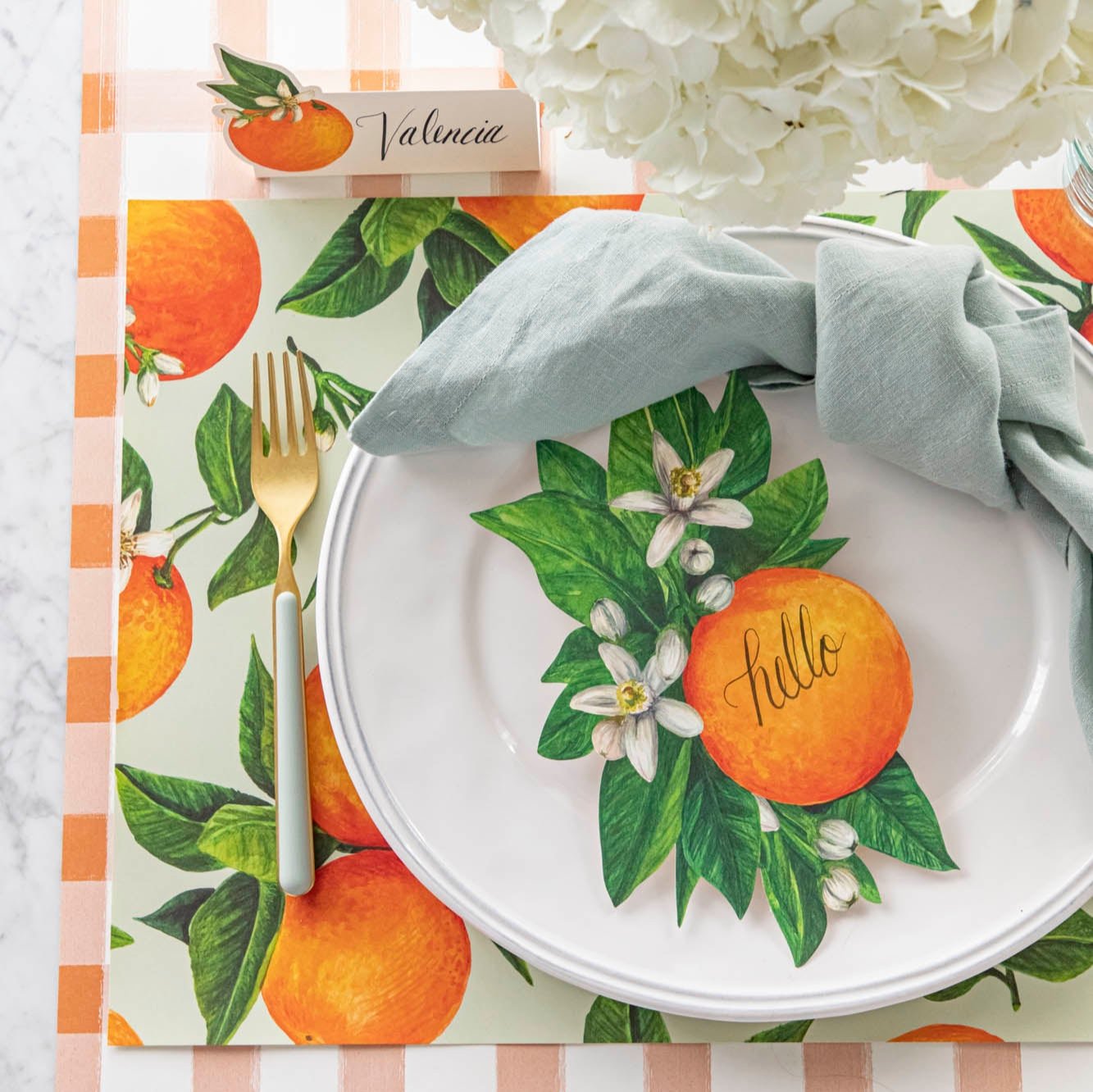 An elegant table setting featuring the Orange Blossom Table Accent with &quot;hello&quot; written on it and coordinating Orange Orchard Placemat and Orange Table Accent.