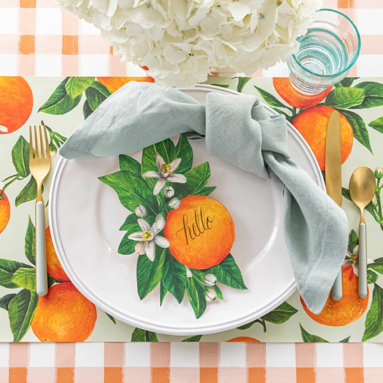 An elegant, citrus themed table setting featuring the Orange Painted Check Runner paired with Orange Orchard Placemat and Orange Table Accent.