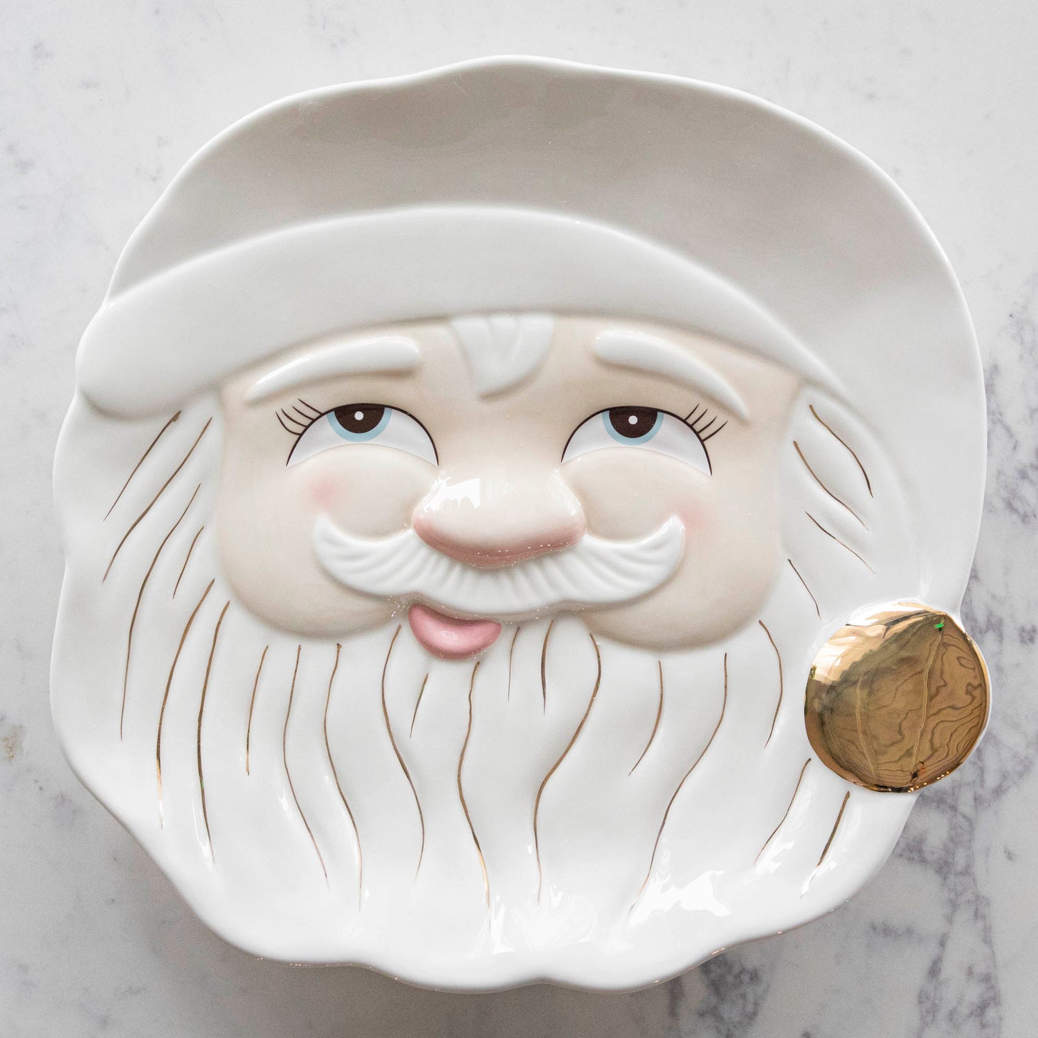 A close up of the Papa Noel Cookie Platter showing his jolly face and hand-painted gold details in the beard and pom of the hat.