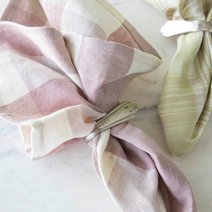 Close up of the Vintage Rose Buffalo Check Cloth Napkin in a silver napkin ring, next to the Grapefruit Plaid napkin.