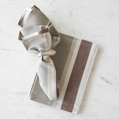 Oak Stone Cloth Napkin in a vintage silver napkin ring on top of the same napkin, on a marble table.