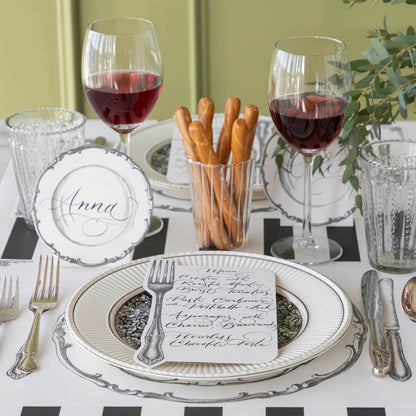 Vintage Fork Table Card with a menu written on it, resting on dinner plates on an elegant table setting for two.