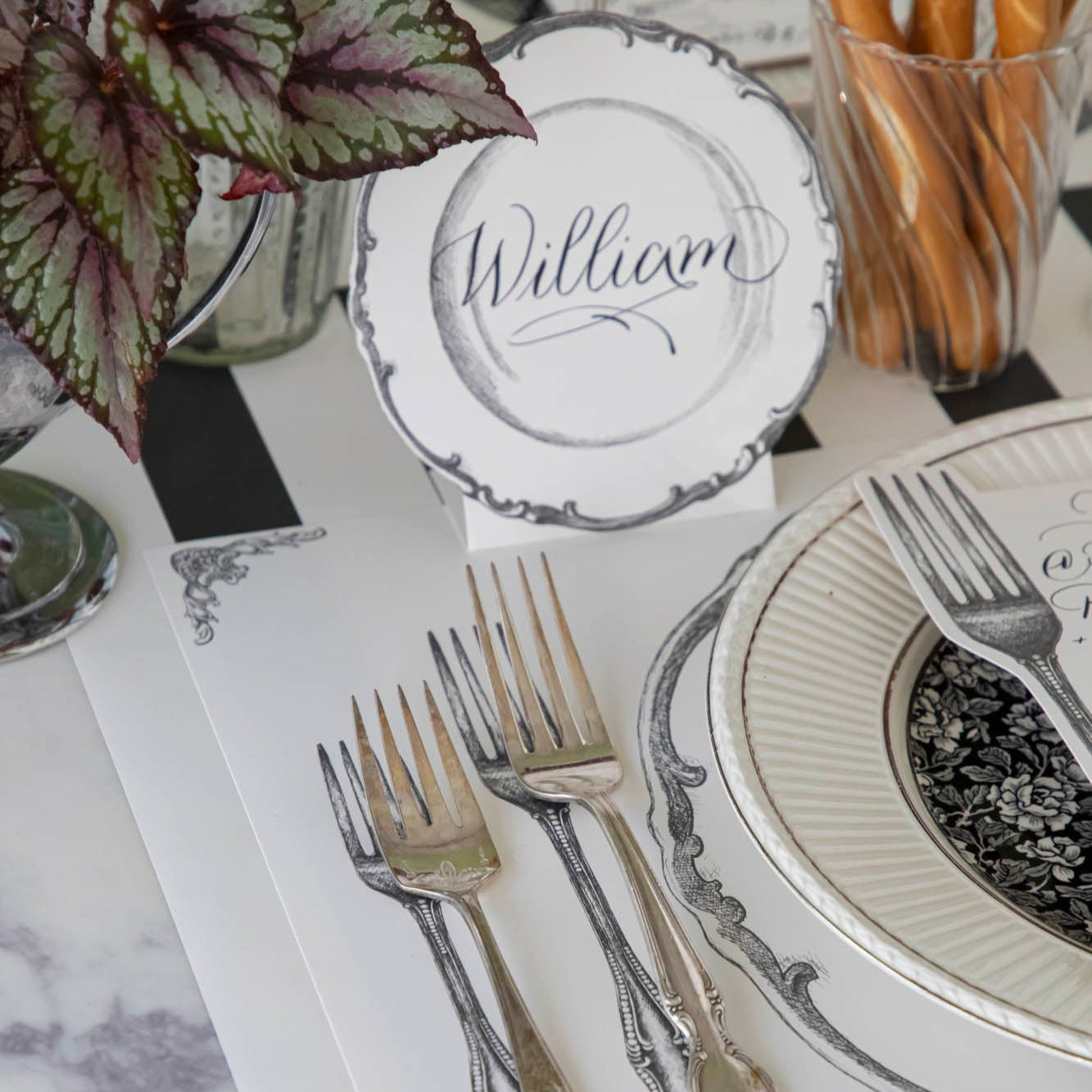 Vintage Plate Place Card with &quot;William&quot; written on it, behind a place setting for one.